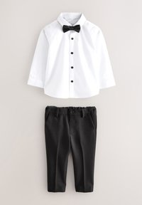 Chemise blanche à manches longues avec boutons noirs et nœud papillon assortie à un pantalon formel noir pour enfant, sur un fond uni.