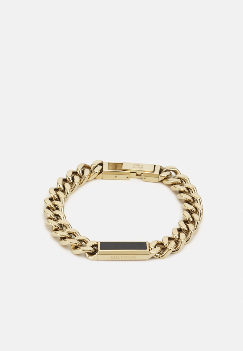 Goldkette-Armband mit großen Gliedern, einem rechteckigen schwarzen Akzent und einem gravierten Verschluss. Glatte Textur mit polierter Oberfläche.