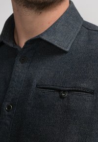Donkerblauwe blouse met knopen, gemaakt van een geweven stof, met een borstzak met klep, een puntige kraag en zwarte knopen.