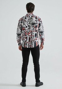 Chemise à manches longues avec un motif rayé noir et blanc, ornée d'impressions léopard et florales en rouge et gris, fabriquée en tissu léger.