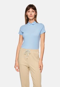 Light blue polo shirt with a collar, paired with beige jogger pants featuring a drawstring. Smooth fabric and casual fit.