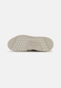 Adidas sneaker sole in beige with hexagonal patterns and textured accents, featuring a brand logo and varying surface textures.