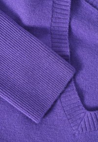 Pullover viola lavorato a maglia con colletto e polsini a costine, texture morbida e tessuto liscio, che presenta diversi motivi di lavorazione nella sua progettazione.