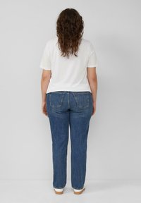 Niebieskie dżinsy o prostym kroju z średnim stanem, z dwoma tylnymi kieszeniami, zestawione z gładką białą koszulką.