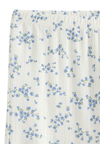 Λευκό ύφασμα με μικρές μπλε λουλουδένιες ομάδες και διακριτικές κάθετες υφασμάτινες ρίγες, με εμφανή ελαστική ζώνη στο πάνω μέρος.