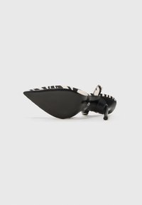 Pointed-toe high heel shoe with a black and white zebra print fabric upper and a black sleek stiletto heel. Smooth texture, minimalistic design.