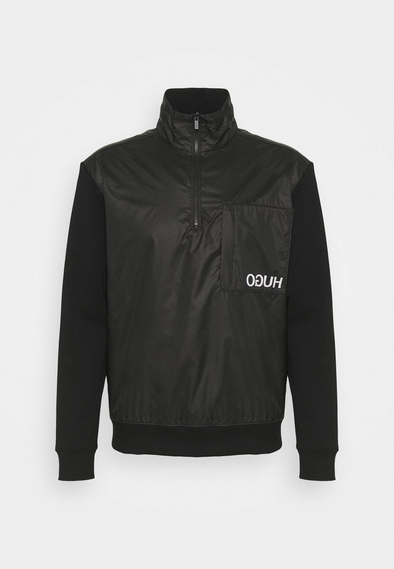 Pull noir à demi-fermeture éclair à l'avant, col montant, manches longues, grande poche poitrine gauche avec logo blanc "HUGO" inversé.