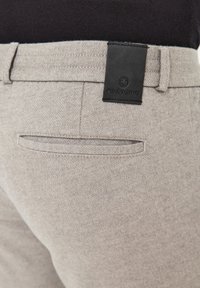 Hellgraue Hose aus strukturiertem Stoff, mit einer Gesäßtasche und einem schwarzen Lederetikett mit dem Markennamen "redpoint".