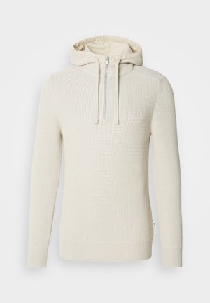 Krēmkrāsas kapuci džemperis ar teksturētu adījumu, puszipu un ribveida aprocēm un apakšu. Aprīkots ar vieglu iekšējo oderi.