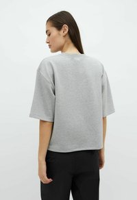 Grauer, gekürzter Sweatshirt mit kurzen Ärmeln, aus weichem Material. Hat einen runden Ausschnitt und eine subtile Textur.