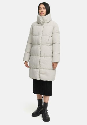 Light grey puffer coat with high collar, rectangular quilted pattern, side pockets, and a mid-length design, paired with a black ribbed skirt and chunky black boots.