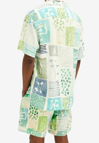 Kort mouw shirt en short set van lichte stof met een kleurrijk patchworkontwerp in groen- en blauwtinten met diverse vormen en patronen.