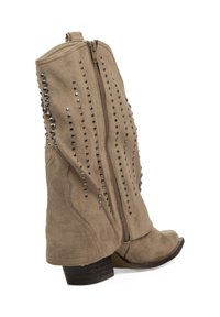 Bota alta hasta la rodilla en gamuza color canela con tachuelas plateadas decorativas a lo largo de la costura de la cremallera, punta puntiaguda y tacón bajo apilado.