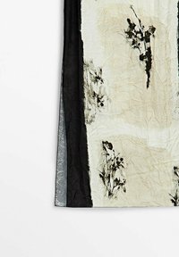 Section de tissu beige et blanc avec des imprimés floraux noirs et des bordures verticales noires et grises, montrant une texture froissée.