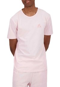 T-shirt in cotone rosa chiaro con maniche corte e scollatura rotonda. Presenta un piccolo logo sul petto. Tessuto morbido e vestibilità casual.