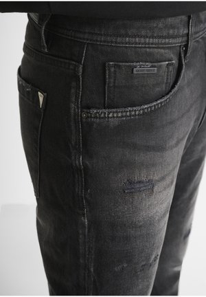 Zwarte denim jeans met een vervaagde afwerking, voorzien van versleten plekken, een label op de achterzak en een licht taps toelopend ontwerp. Verstevigingsstiksels.