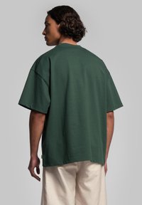 Grön oversized T-shirt med rund halsringning, korta ärmar och avslappnad passform. Bomulls tyg med en mjuk textur. Har en liten etikett vid fållen.