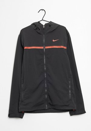 Zwarte Nike-jas met volledige rits en capuchon, met een koraalkleurige horizontale streep over de borst, een koraalrode Nike Swoosh-logo op de linkerborst en ritszakken aan de zijkant.