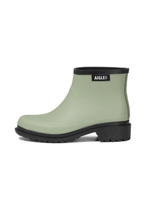 Bota de goma verde mate hasta el tobillo con suela, tacón y ribete negros, con una etiqueta negra con la palabra "AIGLE" cerca de la parte superior.