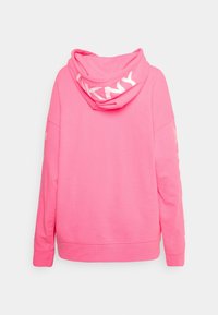 Růžová mikina s uvolněným střihem, vybavená velkou kapucí a bílým potiskem loga na zádech a rukávech. Hladká bavlněná látka, žebrované manžety.