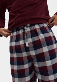 Røde og marineblå ternede pyjamasbukser med elastisk linning og justerbar snor. Stoffet ser blødt ud med kontrasterende ternede mønstre.