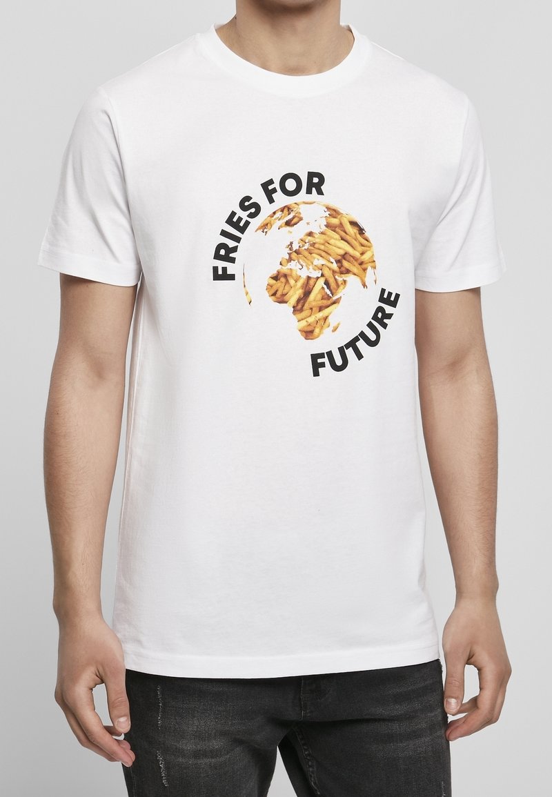 Osoba v bílém tričku s globem z hranolků a textem "Hranolky pro budoucnost" na přední straně, zkombinované s černými džíny.