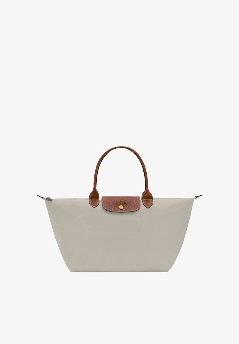 Beige tote bag with brown leather handles and flap, gold button closure, and a zippered top opening.