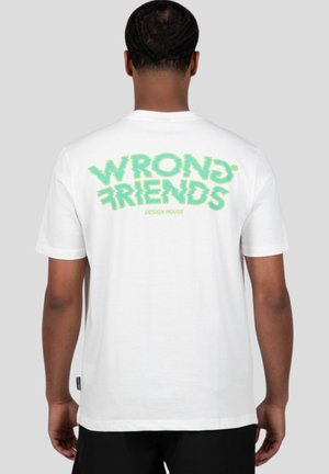 Camiseta de algodón blanca con la frase "WRONG FRIENDS" en texto gráfico verde en la parte de atrás, con un corte holgado y mangas cortas.