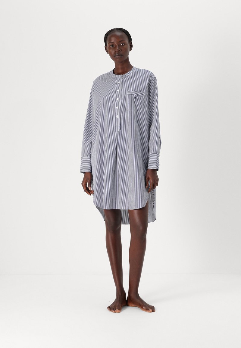 Camisola de noite às riscas, com botões, em azul e branco, feita de tecido leve. Possui mangas longas e um bolso no peito. A bainha é ligeiramente mais longa na parte de trás.