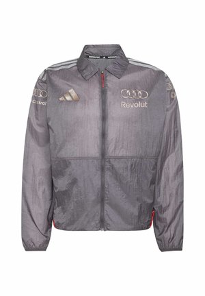 Giacca leggera grigia Motorsport con strisce Adidas, anelli Audi, loghi Revolut e Castrol, zip frontale e polsini elastici.