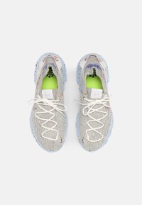 Sportovní boty s horní částí v světle šedé textuře, modrozeleně tečkovanou podrážkou, bílými tkaničkami a jasně zelenou podšívkou s dekorativními akcenty.