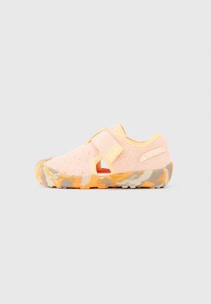 Pink mesh water shoes with a Velcro strap, open sides, and a textured orange and gray sole. Lightweight and designed for aquatic activities.