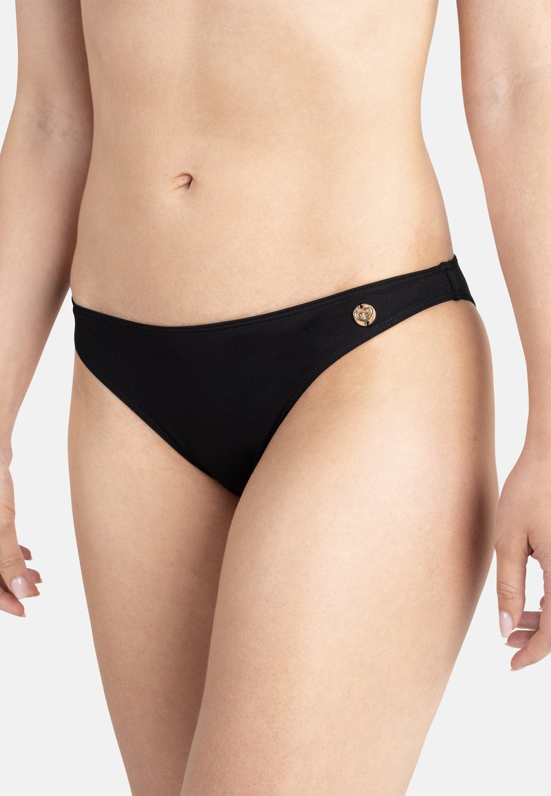 Bas de bikini noir en tissu lisse, présentant une coupe étroite et un petit logo circulaire doré sur le côté.
