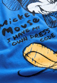 Blue cotton t-shirt featuring a graphic of Mickey Mouse with black outlines and yellow accents, overlaid with the text “I HAVE MY OWN DRESS CODE.”