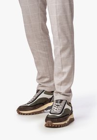 Sneakers con un design multi-materiale in tonalità di marrone e verde, caratterizzati da un tessuto testurizzato e una suola spessa con tasselli per una migliore aderenza.