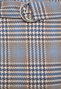 Modrý, hnědý a krémový látkový vzor v tipu houndstooth s připevněnou stříbrnou dvojitou D-kroužkovou sponou na pásku.