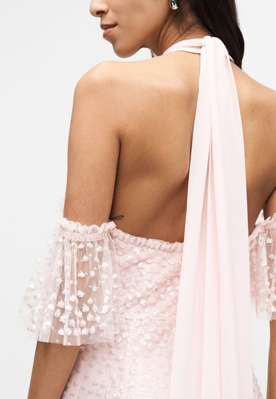 Ροζ φόρεμα με παγιέτες, με διαφανείς, βολάν μανίκια και λεπτομέρεια φιόγκου στην πλάτη. Ομαλό ύφασμα με υφή και ανοιχτό σχέδιο στην πλάτη.