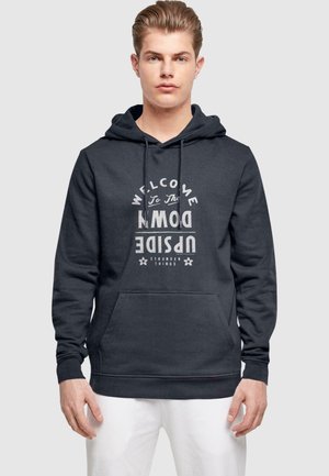 Dunkelgrauer Kapuzenpullover aus weichem Material mit einer vorderen Tasche und weißem grafischem Text, der "WILLKOMMEN IM UPSIDE DOWN" lautet.
