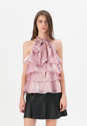 Gerimpeld haltertop in zachtroze satin met een striknek en gelaagd ontwerp. Gecombineerd met een aansluitende zwarte leren rok.