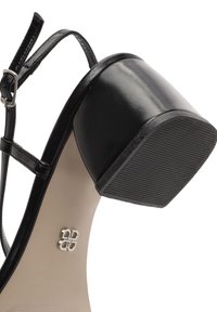 Sandal in pelle nera con tacco alto, punta arrotondata, sottile cinturino alla caviglia e suola in gomma testurizzata. Presenta un dettaglio del logo argentato sulla soletta.