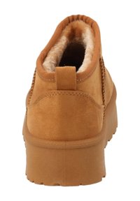 Stivaletto alla caviglia in camoscio color miele con interno imbottito, suola spessa in gomma e linguetta posteriore per facilitare l'indossamento e la rimozione.