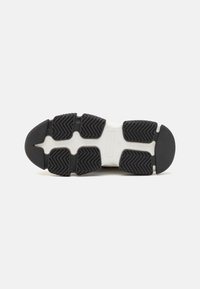 Sole in gomma nera per sneaker con motivi testurizzati per una migliore trazione, dotata di una soletta bianca e un design elegante e moderno.