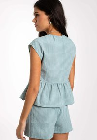 Top peplum de cuadros vichy azul con mangas cortas, cintura ajustada y pantalones cortos a juego, hecho de una tela texturizada. Diseño simple, estilo ligero.