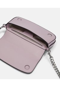 Różowa skórzana torebka crossbody z srebrnym łańcuszkiem, z otwartą klapą, wewnętrzną kieszenią i kontrastującymi czarnymi krawędziami.