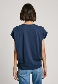 Námořnická modrá tričko s krátkým rukávem, volného střihu a kulatým výstřihem; měkká bavlněná látka; jednoduché švy na ramenou.