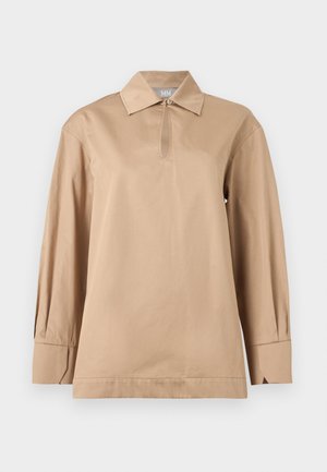 Beige long-sleeve shirt with a pointed collar, keyhole neckline with button, and wide cuffs on plain background.