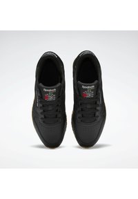 Reebok tenisky z čiernej syntetickej kože, s perforovanou špičkou, čiernymi šnúrkami a gumovou podrážkou. Klasické logo a dizajnové akcenty.