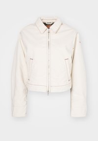 Korte witte spijkerjas met een ritssluiting aan de voorkant, twee zijzakken, rode stiksels en een klassiek kraagontwerp.