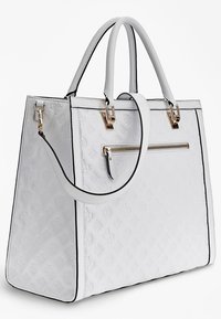Sac fourre-tout en cuir blanc avec un motif floral gaufré, des accents en matériel doré, des poignées supérieures et une poche extérieure zippée avec un contour noir.