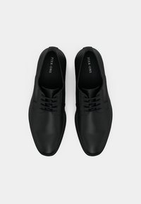 O pereche de pantofi de dress din piele neagră, cu șireturi, cu marca "Pier One" vizibilă pe tălpile interioare, expuși pe un fundal alb.